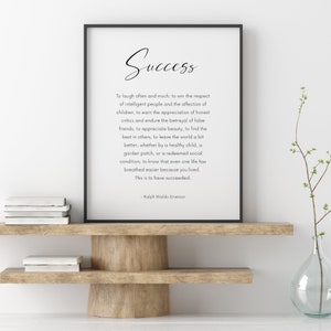 Puede incluir: Impresi&oacute;n enmarcada con la palabra "Success" en escritura cursiva. La impresi&oacute;n presenta una cita de Ralph Waldo Emerson. Se encuentra sobre una estanter&iacute;a de madera con libros y un jarr&oacute;n.