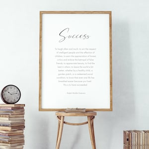 Puede incluir: Un marco de madera con la palabra "Success" en escritura. La impresi&oacute;n presenta una cita de Ralph Waldo Emerson sobre un fondo blanco. Un peque&ntilde;o reloj y una pila de libros son visibles.