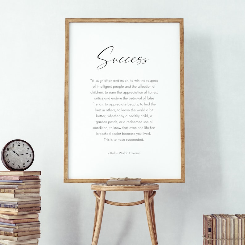 Puede incluir: Un marco de madera con la palabra "Success" en escritura. La impresi&oacute;n presenta una cita de Ralph Waldo Emerson sobre un fondo blanco. Un peque&ntilde;o reloj y una pila de libros son visibles.