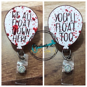 May include: Two badge reels with balloon-shaped designs. One reads "WE ALL FLOAT DOWN HERE" and the other says "YOU'LL FLOAT TOO." Both have a white background with red splatter and black text. The reels have a clear plastic strap and a glittery button.