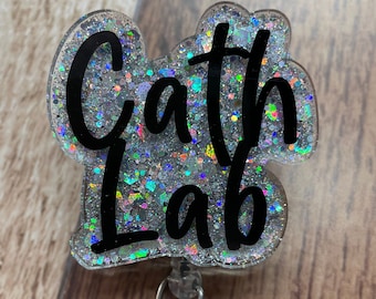 May include: A silver glitter badge holder with a black "Cath Lab" text. The badge holder has a clear plastic retractable reel.