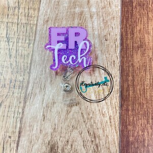 Op de afbeelding: Paarse glitter badge reel met een witte "ER Tech" inscriptie. De reel heeft een transparante plastic behuizing en een zilveren intrekbaar koord.