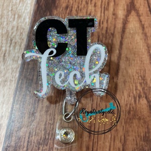 May include: A silver glitter badge holder with a black and white "CT Tech" design. The badge holder has a clear plastic retractable cord and a crystal-like button.