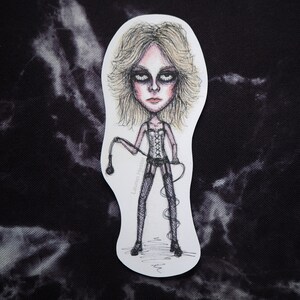 Könnte beinhalten: Eine Schwarzweißillustration einer Frau mit langen blonden Haaren, die ein schwarzes Korsett und Netzstrümpfe trägt. Sie hält eine Peitsche in ihrer rechten Hand. Die Illustration ist auf weißem Hintergrund.