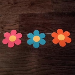 Peut inclure: Une guirlande de fleurs en papier colorées avec des fleurs vertes, roses, bleues et violettes. Chaque fleur a un centre jaune.