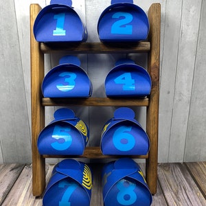 May include: Eight blue gift boxes with numbers 1 through 8 printed on them are displayed on a wooden shelf. Each box has a gold menorah design on the front.