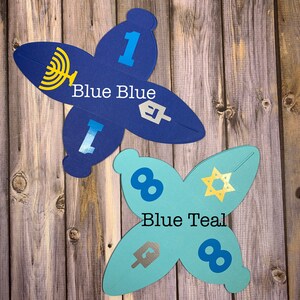 May include: Two blue and teal paper gift boxes shaped like butterflies. The blue box has the number "1" and the text "Blue Blue" on it. The teal box has the number "8" and the text "Blue Teal" on it.