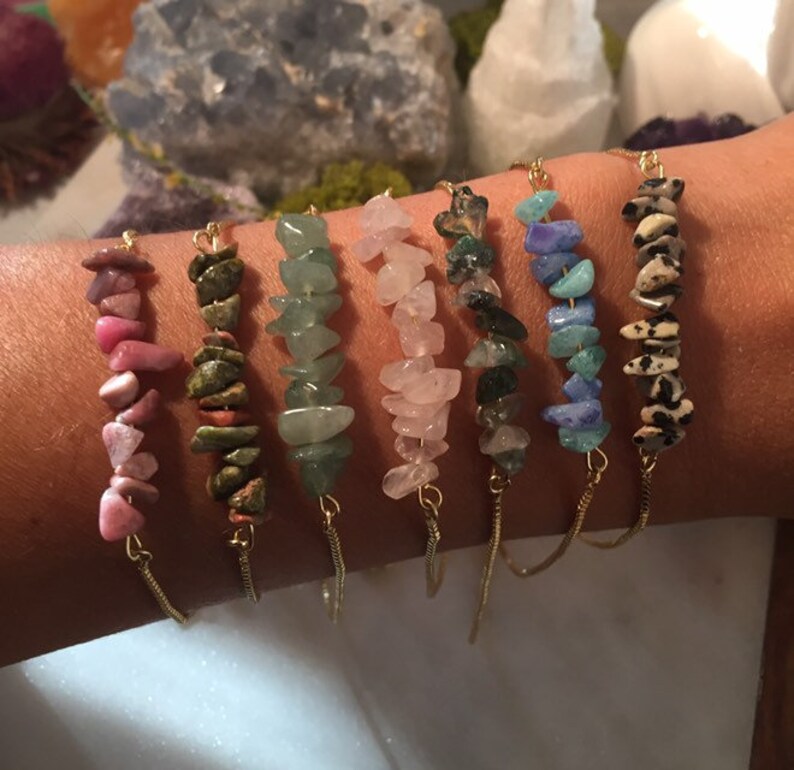 May include: Seven gold chain bracelets with different colored gemstone chips. The bracelets feature pink, green, light green, rose quartz, dark green, blue, and brown and white chips.