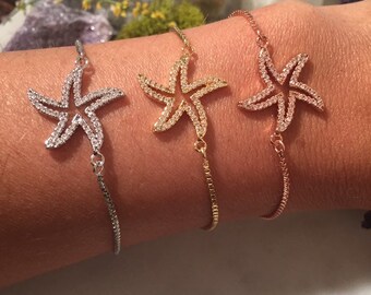 May include: Three adjustable bracelets with a silver, gold, and rose gold chain. Each bracelet features a sparkling starfish charm.