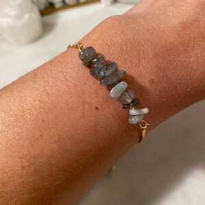 May include: A gold chain bracelet with a row of gray and white gemstone chips.