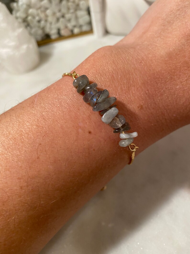 May include: A gold chain bracelet with a row of gray and white gemstone chips.