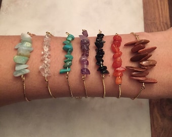 May include: Seven gold chain bracelets with different colored gemstone chips. The bracelets feature aquamarine, clear quartz, turquoise, amethyst, black onyx, carnelian, and sandstone.
