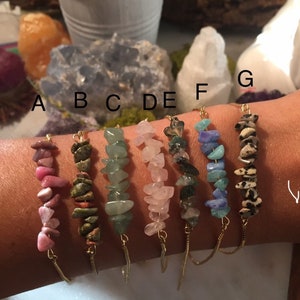 May include: Seven gold chain bracelets with different colored gemstone chips. The bracelets are labeled A through G.