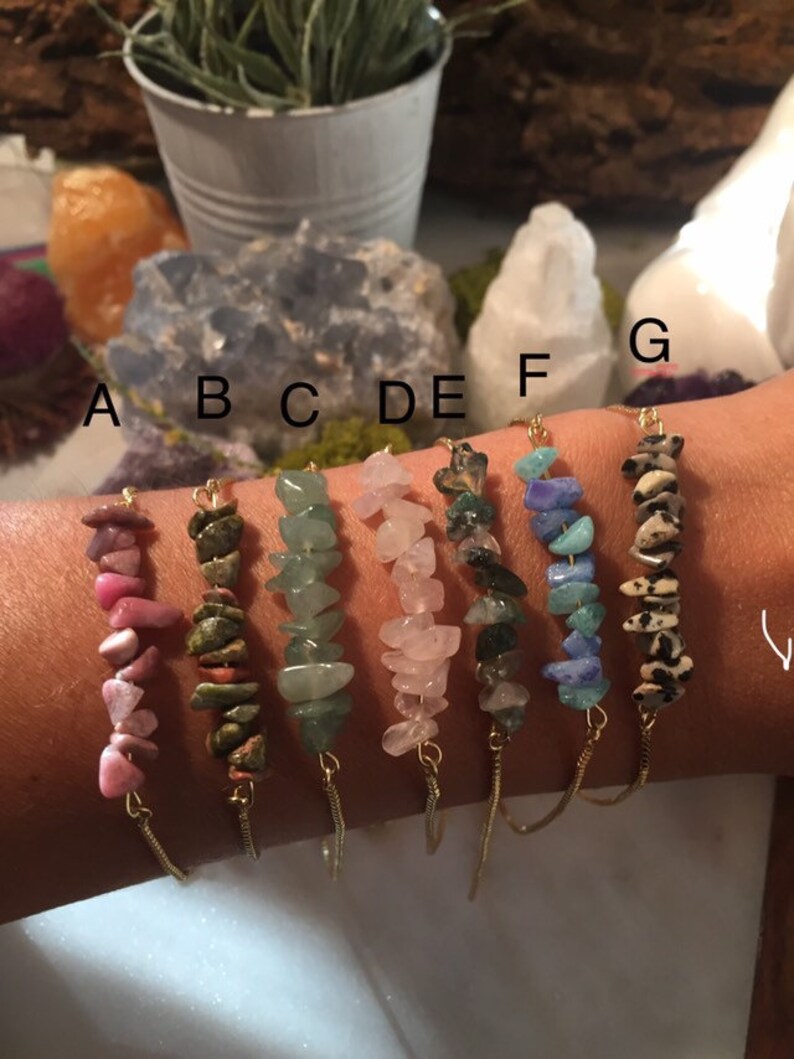 May include: Seven gold chain bracelets with different colored gemstone chips. The bracelets are labeled A through G.