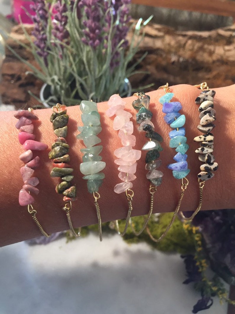 May include: Seven gold chain bracelets with different colored gemstone chips. The bracelets feature pink, green, light pink, green and black, blue, and brown and white gemstone chips.