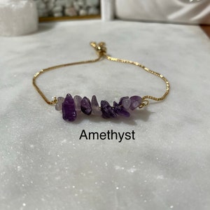May include: A gold chain bracelet with a cluster of amethyst stones. The bracelet is adjustable and has a sliding knot closure. Amethyst.