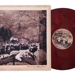 May include: A red vinyl record with a black and white image of a group of people standing in front of a building. The text "Mama Said String Band" and "Seasons of Change" is printed on the record label.