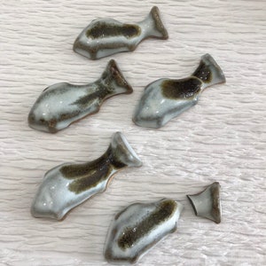 以下が含まれることがあります： 白と茶色のセラミック製の魚の形をした置物5つ。魚は釉薬がかけられており、斑点模様になっている。1つの魚が半分に割れている。