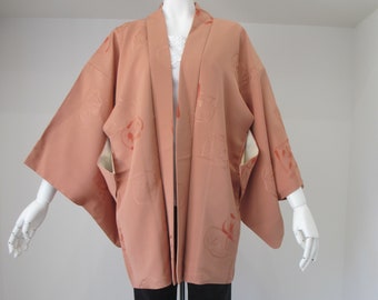 Puede incluir: Un kimono de color melocotón con un estampado floral. El kimono está hecho de una tela suave y sedosa y tiene un corte holgado.