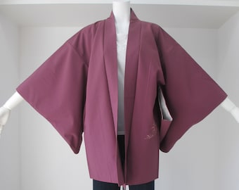 Puede incluir: Un kimono granate con mangas largas y una prenda interior blanca. El kimono se muestra en un maniquí con pantalones negros.