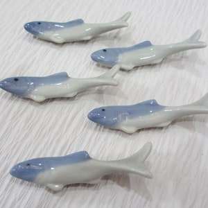 May include: Set of five ceramic fish chopsticks rests. The fish are white with a light blue glaze and have black eyes.