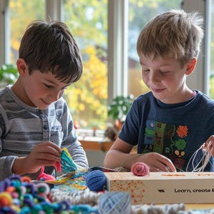 May include: Two children are engaged in a craft activity, working with colourful yarn and string. A box with the text "Learn, create & share" is on the table. The setting is indoors, with natural light from a window, suggesting a creative project.