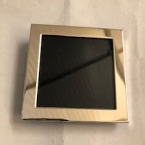 以下が含まれることがあります： 正方形の開口部のある銀色の写真フレーム。フレームは狭い縁取りと滑らかで磨かれた仕上げになっています。