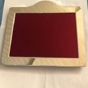 以下が含まれることがあります： アーチ型のトップと赤いベルベットの裏地が付いたシルバーのフォトフレームです。