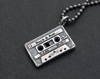 May include: Silver necklace with a cassette tape pendant. The pendant has the words "Rock & Roll" and "Music" engraved on it.