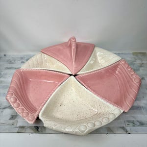May include: A vintage ceramic serving dish with five sections. The dish is white with pink accents and has a speckled glaze. The sections are shaped like triangles and have a raised edge.