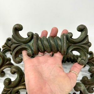 May include: Set of six antique-style cabinet pulls with a twisted rope design and ornate scrollwork. The pulls are made of metal and have a green patina finish.