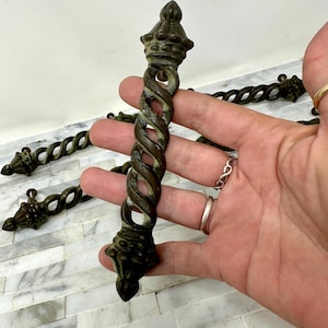 May include: Four antique bronze cabinet drawer pulls with a twisted rope design and ornate crown-shaped tops.