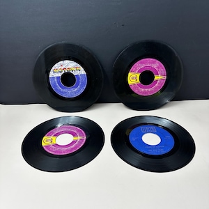 May include: Four black vinyl 45 RPM records arranged in a two-by-two grid. The top left record features a Motown label, the top right and bottom left have purple labels with yellow accents, and the bottom right record has a blue Mala label.