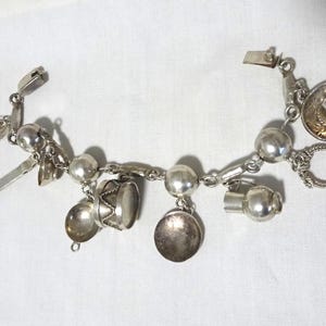 Peut inclure: Un bracelet de charme argenté avec divers breloques, dont un sombrero, un tambour et d'autres éléments décoratifs. Le bracelet est en métal argenté et possède une fermeture à fermoir. Les breloques détaillées ajoutent une touche unique.