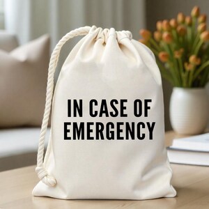 May include: A white canvas drawstring bag with the text "IN CASE OF EMERGENCY" printed in black.