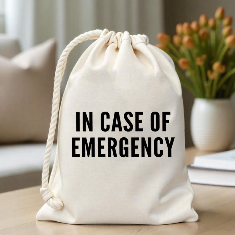 May include: A white canvas drawstring bag with the text "IN CASE OF EMERGENCY" printed in black.