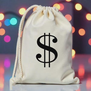May include: A cream-colored drawstring bag with a large black dollar sign printed on the front. The bag has a white rope drawstring closure. The background is blurred with colorful bokeh lights.