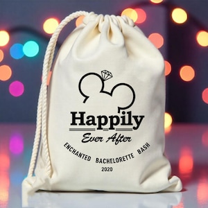 May include: White drawstring bag with black text that reads "Happily Ever After Enchanted Bachelorette Bash 2020". The bag features a black silhouette of Mickey Mouse ears with a diamond ring in the center.