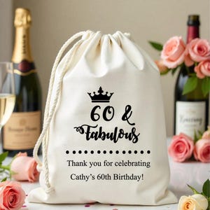 May include: A white cotton drawstring bag with a black crown and the text "60 & Fabulous" printed on it. The bag also has the text "Thank you for celebrating Cathy's 60th Birthday!" printed on it.