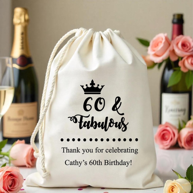 May include: A white cotton drawstring bag with a black crown and the text "60 & Fabulous" printed on it. The bag also has the text "Thank you for celebrating Cathy's 60th Birthday!" printed on it.