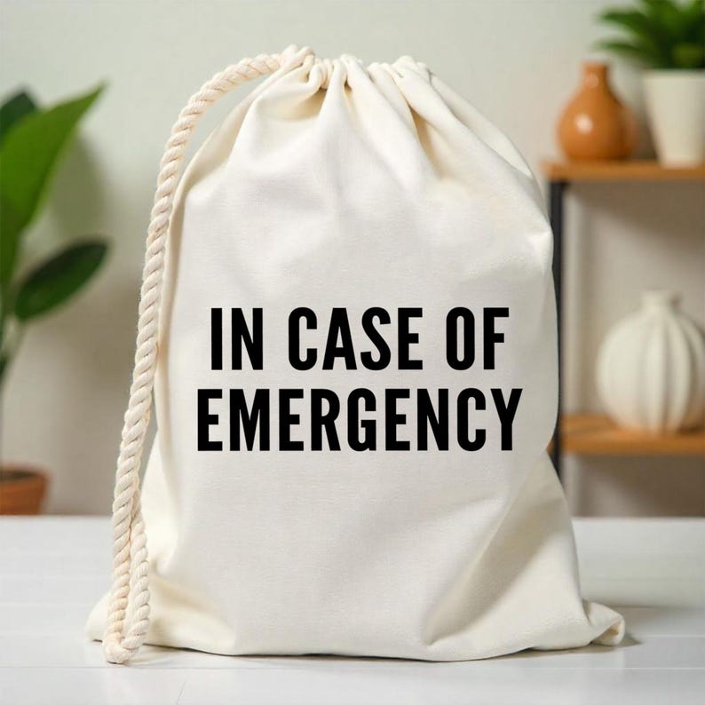 May include: A white canvas drawstring bag with the text "IN CASE OF EMERGENCY" printed in black.