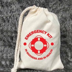 以下が含まれることがあります： 赤いライフセーバーのグラフィックと「Emergency Kit In Sickness And In Health」というテキストが書かれた白いキャンバス製の巾着袋です。