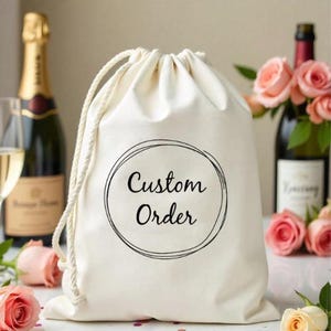 以下が含まれることがあります： 黒い円と「Custom Order」という文字が印刷された白い綿の巾着袋です。