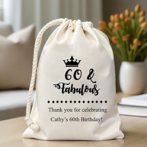 May include: A white cotton drawstring bag with a black crown and the text "60 & Fabulous" printed on it. The bag also has the text "Thank you for celebrating Cathy's 60th Birthday!" printed on it.