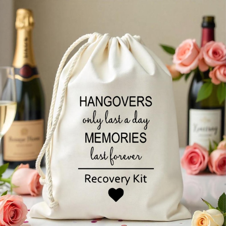 K&ouml;nnte beinhalten: Ein wei&szlig;er Beutel mit Kordelzug und schwarzem Text, der "Hangovers only last a day MEMORIES last forever Recovery Kit" lautet, mit einem schwarzen Herzen unter dem Text.