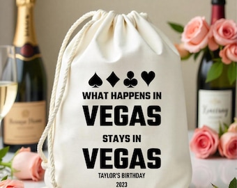 Könnte beinhalten: Weiße Baumwoll-Kordeltasche mit schwarzem Text, der "What happens in Vegas stays in Vegas" und "Taylor's Birthday 2023" lautet. Die Tasche hat außerdem vier schwarze Spielkartensymbole.