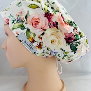 May include: White scrub hat with a floral print featuring pink, white, and burgundy roses. The hat has a drawstring and the text "ScrubLife" is printed on the side.