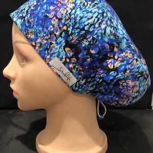 May include: Blue and black patterned scrub cap with a white label that says "Scrublife" on it. The cap has a drawstring.