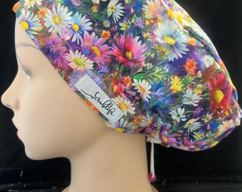 May include: A colorful floral scrub cap featuring a vibrant daisy pattern in shades of pink, purple, yellow, and white. The cap has a white label that says "Scrublife". The cap is designed to be worn in a medical setting.