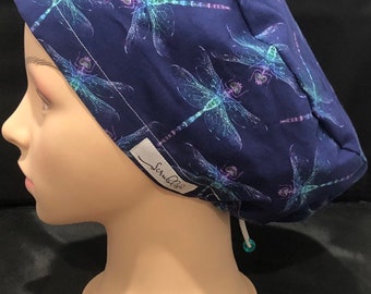 May include: A navy blue scrub hat with a dragonfly print. The hat has a white drawstring and a white label that says "ScrubLife".
